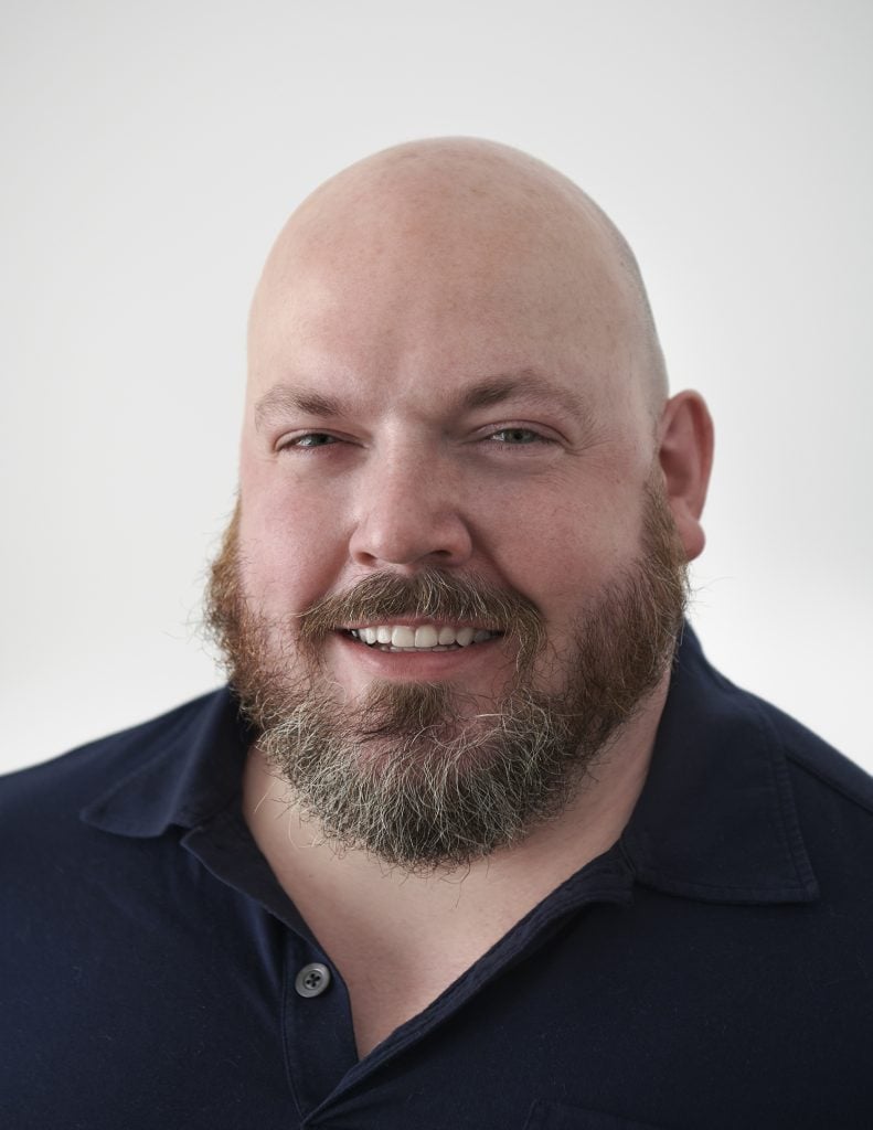 Headshot portrait of Art Enterprise Resources founder James Morrill wearing a black polo tee against a white background.