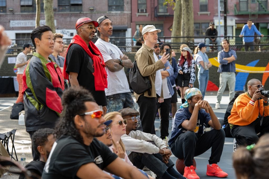 A photograph of a crowd of people on the sidelins watching the final game in the Ball For Art tournament.