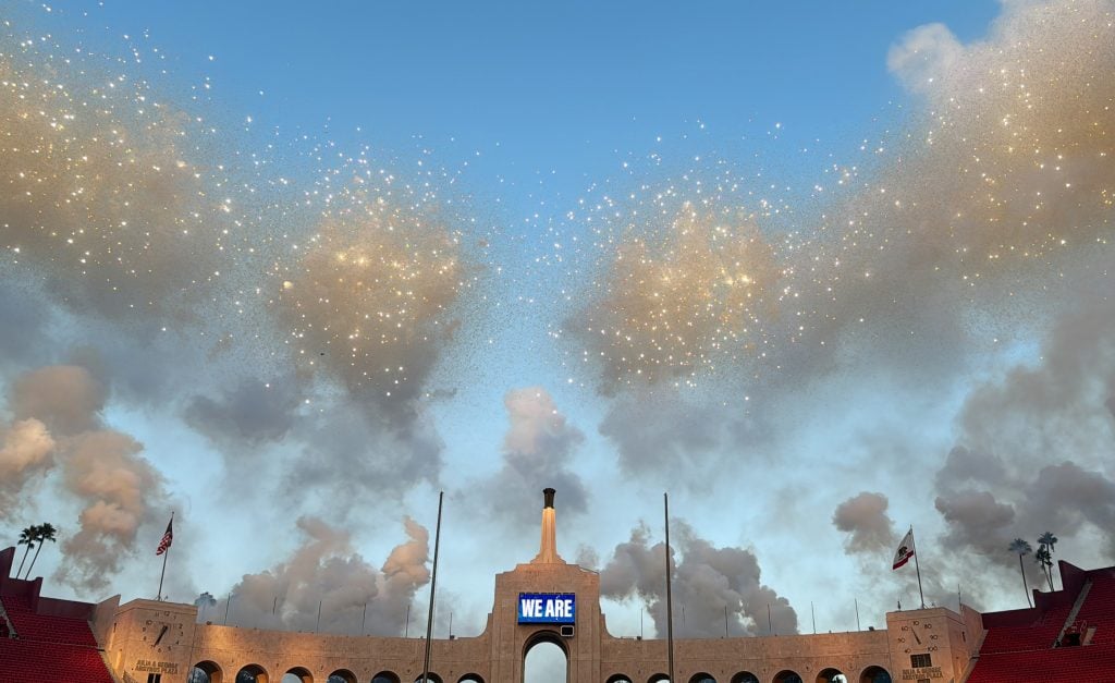 A cloud of fireworks against a structure with a screen that reads 