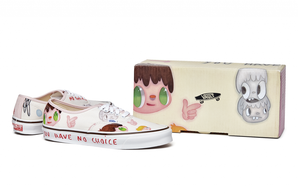 A photo of a pair of low rise sneakers with cartoon designs on them pointing right, towards a box featuring the same designs.