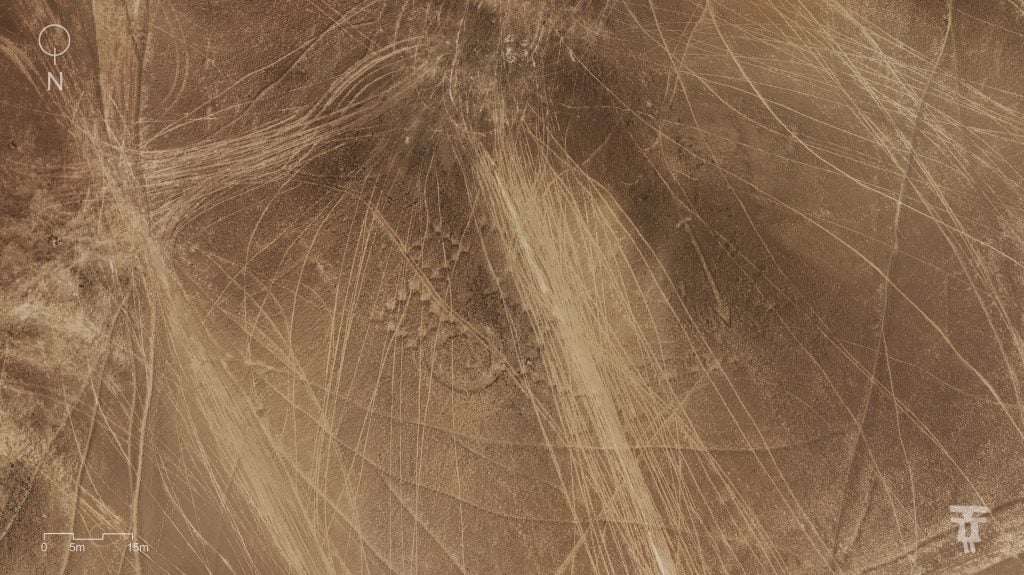 Aerial view of vehicle tracks crisscrossing ancient geoglyphs in a desert landscape