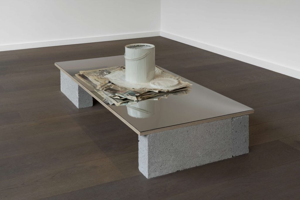 Artwork by artist duo Cullinan Richards showing a low table made of concrete with a series of objects at its center.