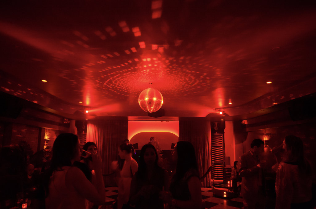 A photograph of a red-lit club, with a disco ball atop it.