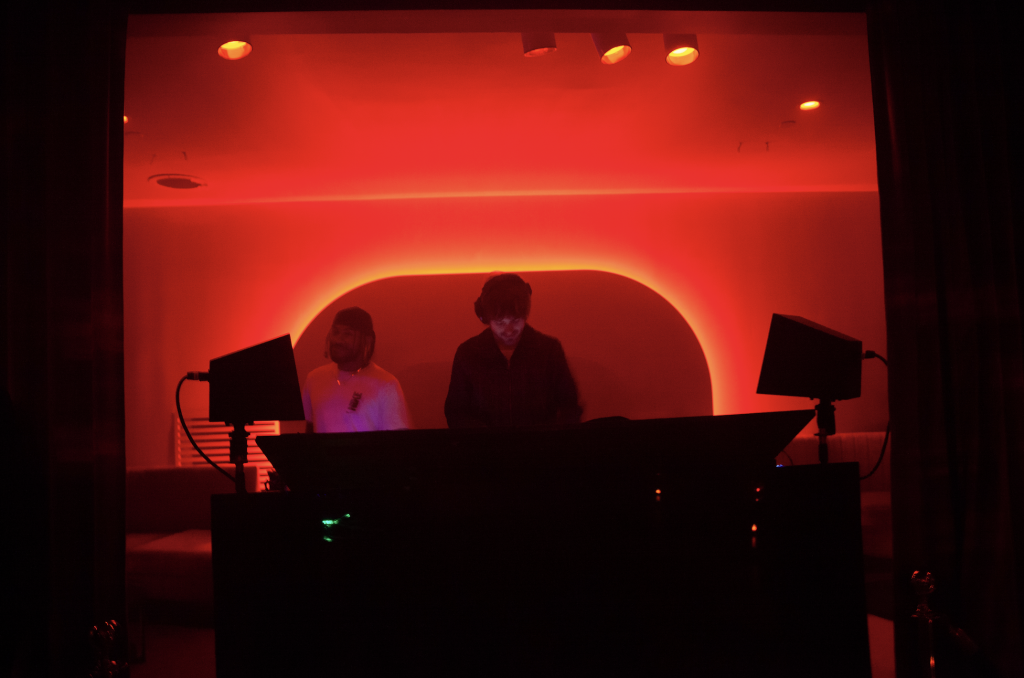 A photo of a DJ spinning in a red-tinged booth.