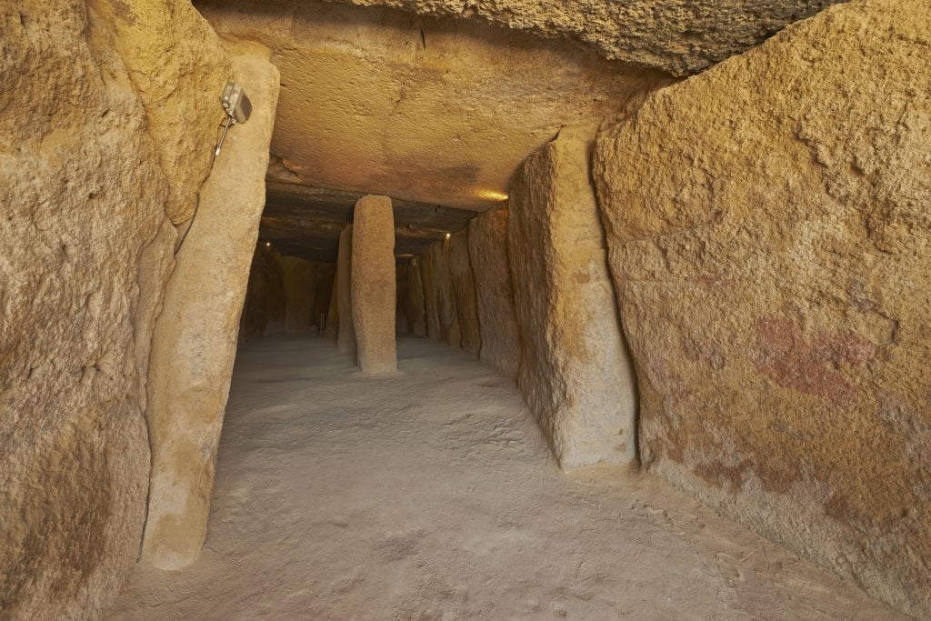 A photograph of the empty, cavernous inside of a Neolithic burial site built from rocks.