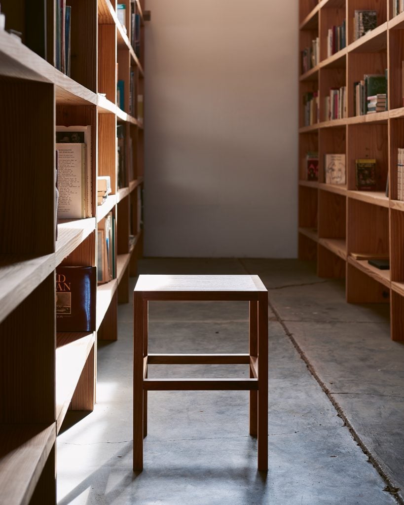 A stool designed by Donald Judd sitting alongside a bookshelf