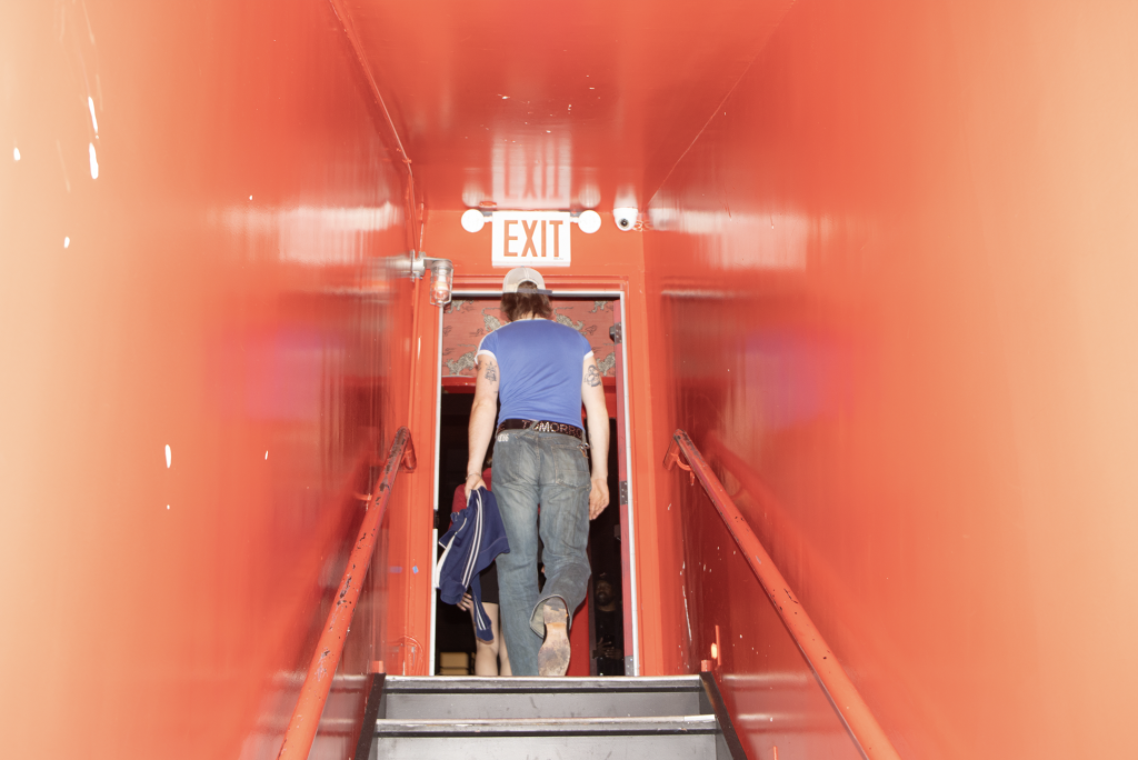 A photo of a man exiting a bright red hallway, up a staircase.