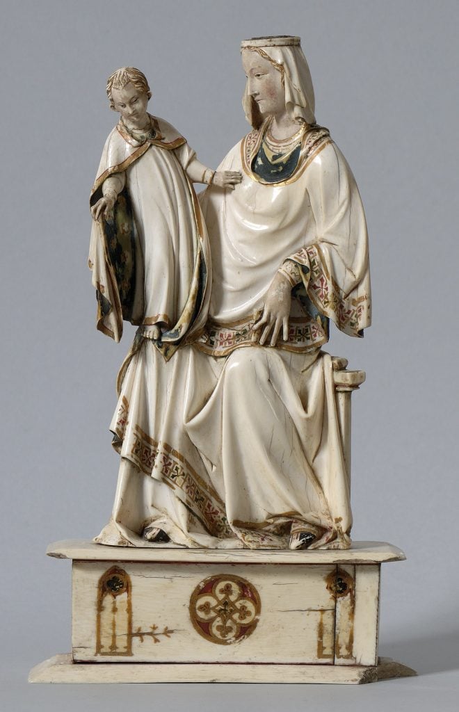 A photo of a white and gold statue depicting a child Christ standing on the seated Virgin Mary's knee.