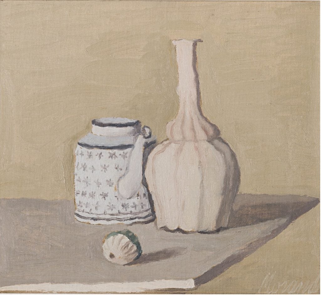 A still life by Giorgio Morandi with two pale vessels and a small cream-colored ball all against a beige background.