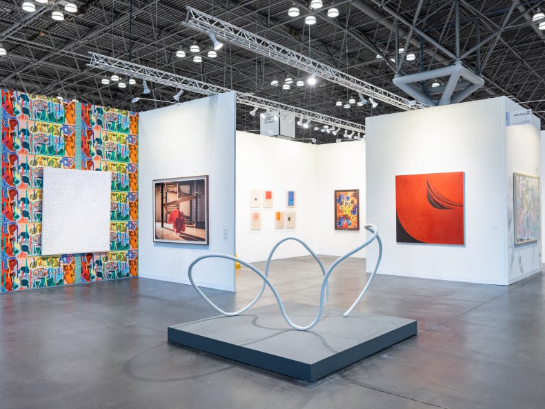 photo of gallery Nara Roesler's booth at the Armory show including a wiry metal sculpture and some paintings on the wall