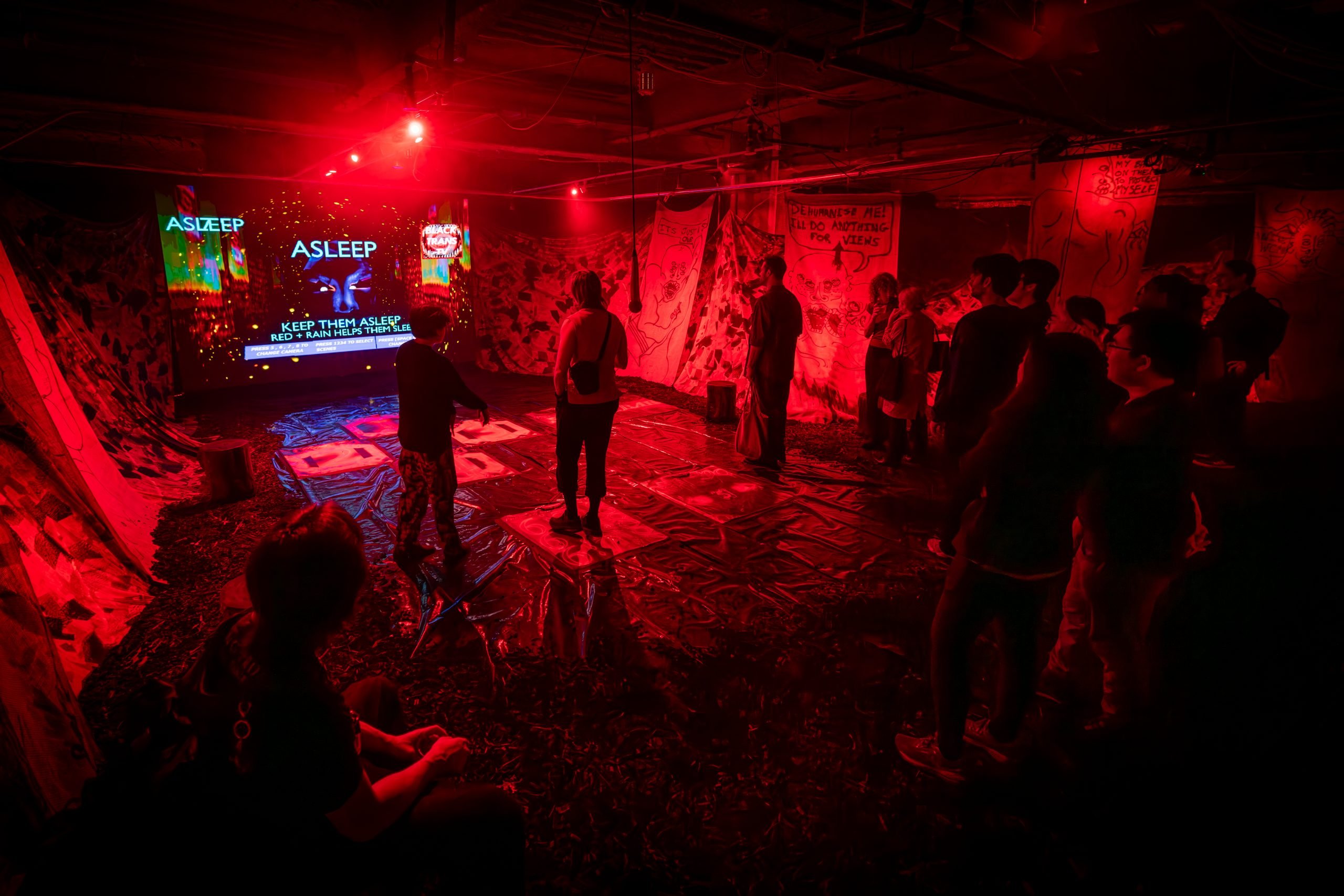 A photograph of guests playing a video game in a dark red room.