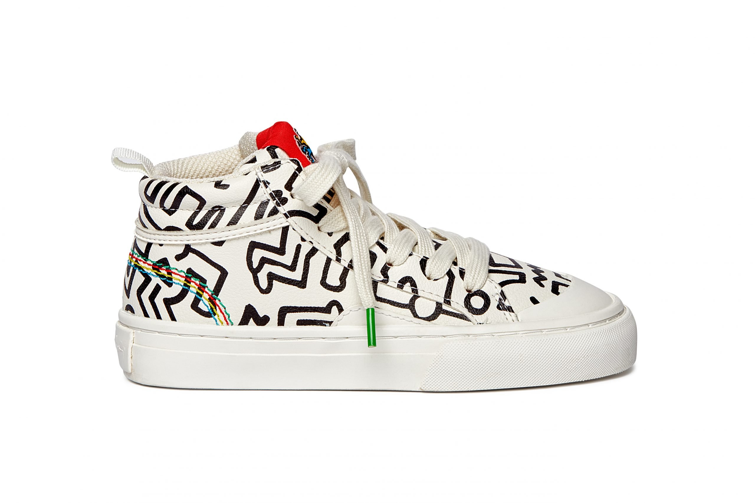 A photo of a white right-hand sneaker with Keith Haring dancing guy designs all over it.