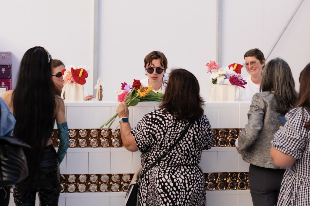 Three guests getting their flowers wrapped at a white checkout counter.