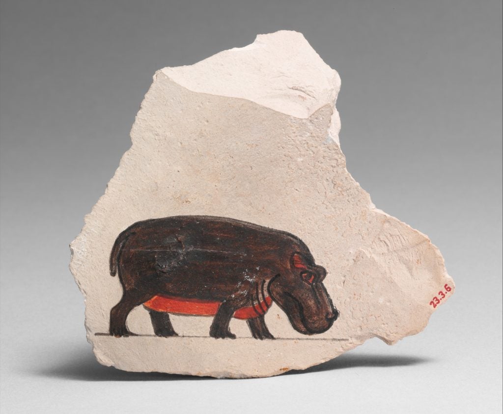 a shard of white limestone on which is painted a single hippopotamus in brown with a bright pink belly