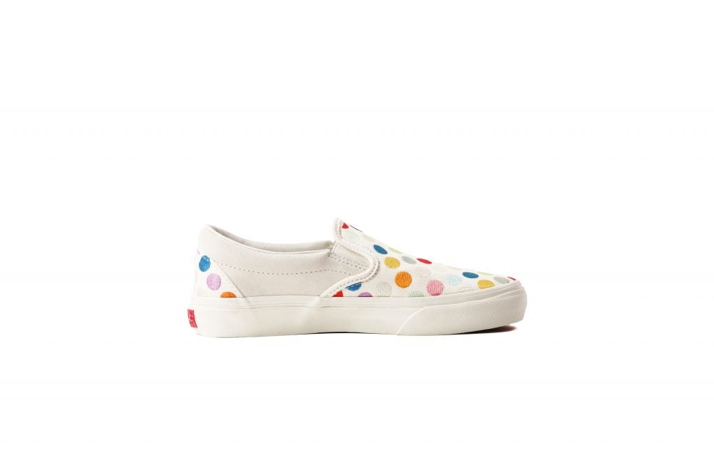 A photograph of a white, left-hand, low-cut shoe with colorful dots on it by Damien Hirst.