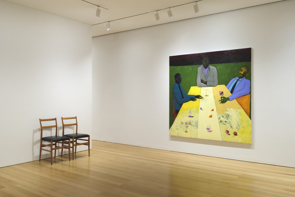 View inside a gallery room with a painting by Lubaina Himid on the right wall and two chairs together against the left wall.