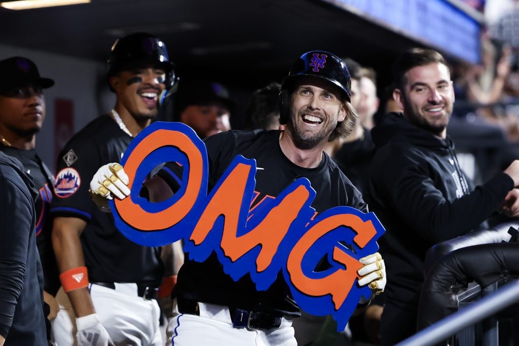 Mets second baseman Jeff McNeil holds an OMG sign. by artist Jeromer McCroy in the dugout after hitting a three-run home run in the sixth inning against the Houston Astros at Citi Field on June 28, 2024.