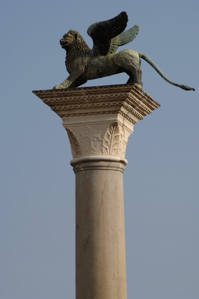 A bronze statue of a winged lion on a stone pedestal