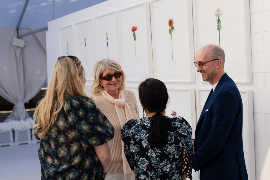 A group of four people, including Marth Stewart, talks amongst the floral plush drawings by Cj Hendry at Flower Market