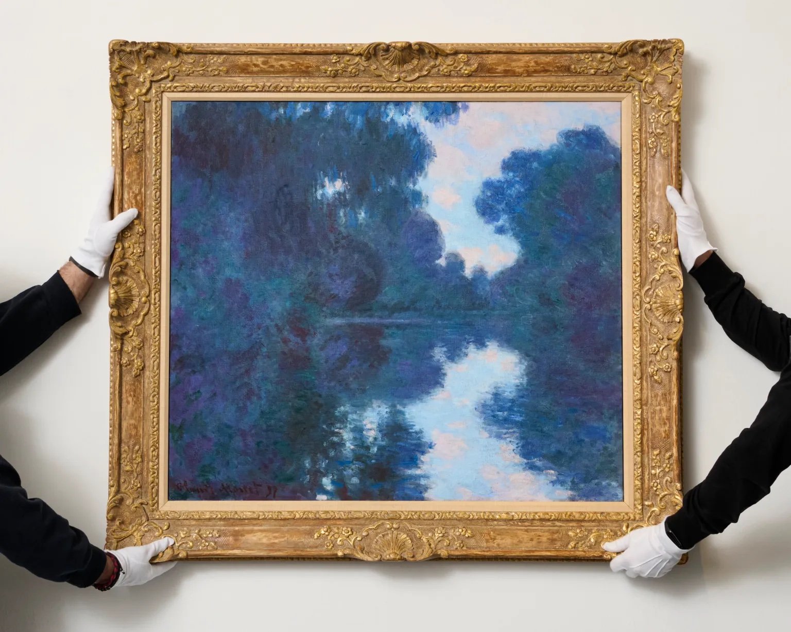 two pairs of white-gloved hands hold a framed painting of the seine river in paris