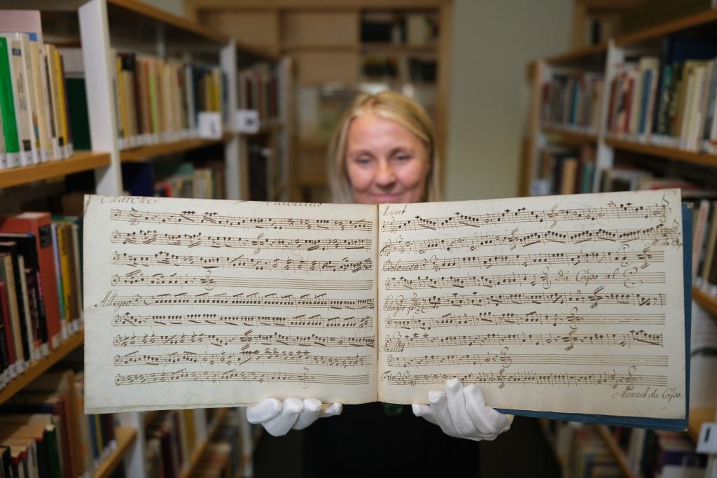 A woman holding open a musical manuscript