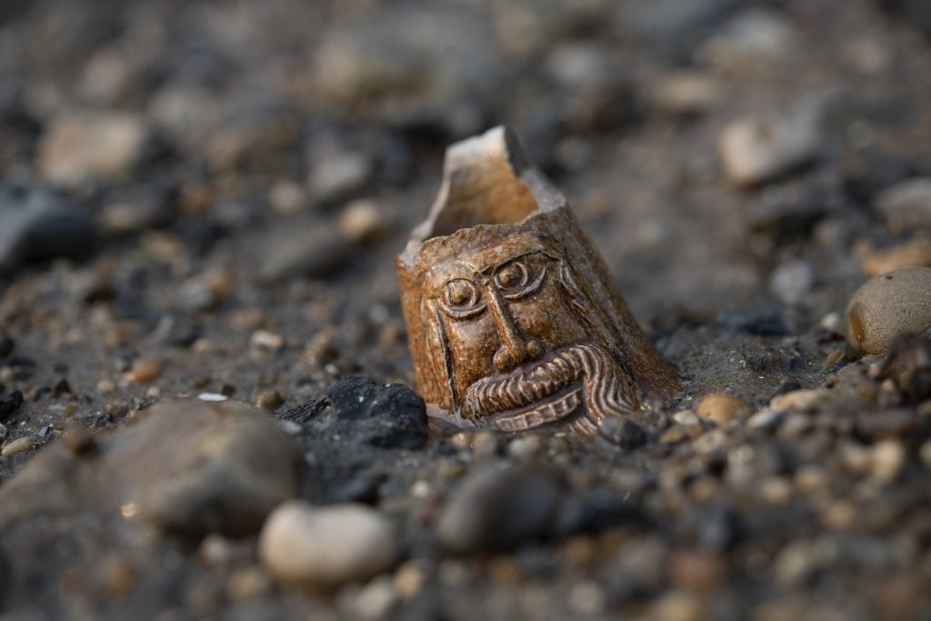 Close-up of a neck of a stoneware bottle with a bearded face poking out of a shore