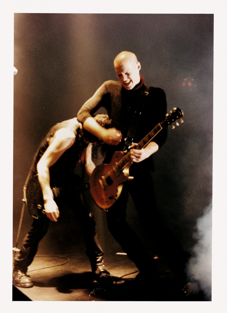 two men on stage one with guitar, the other in headlock