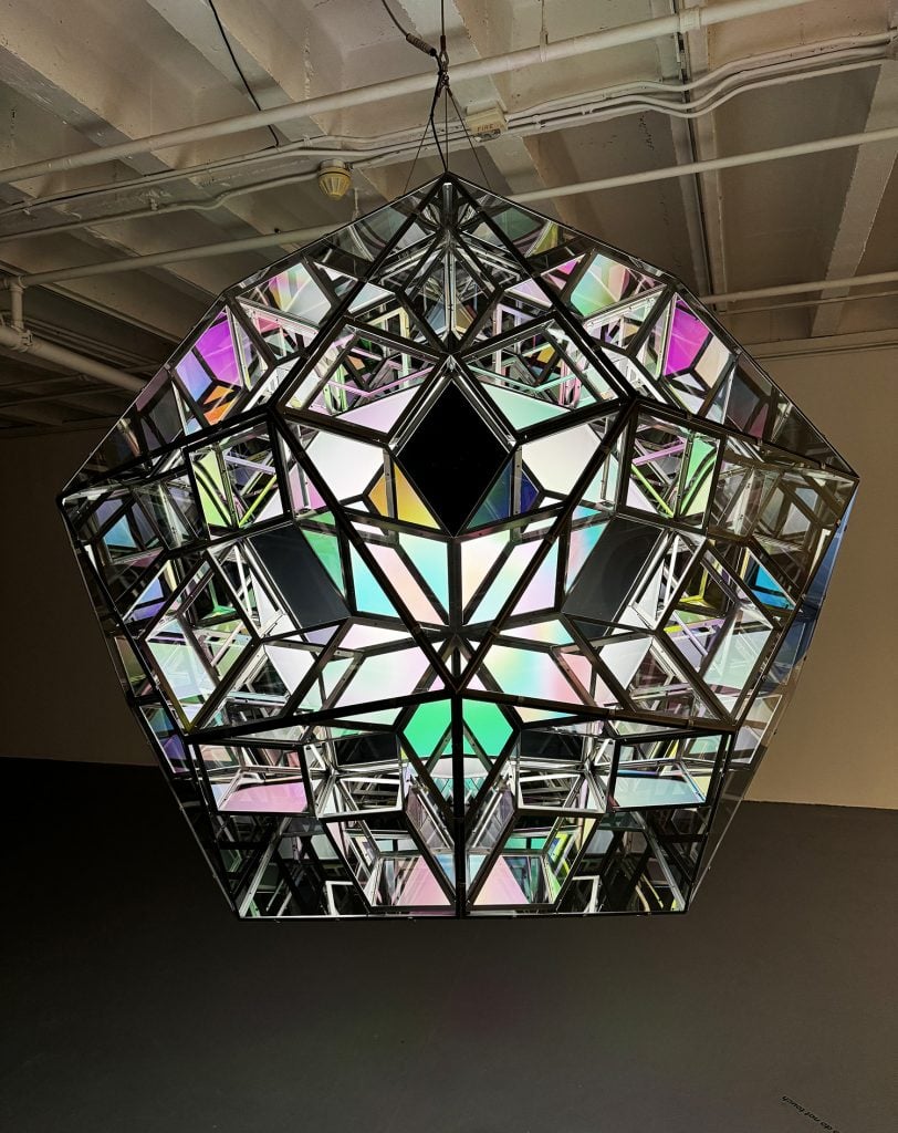 A sculpture of a rhombic triacontahedron, with shiny edges and panels colored in pinks, greens, and blues