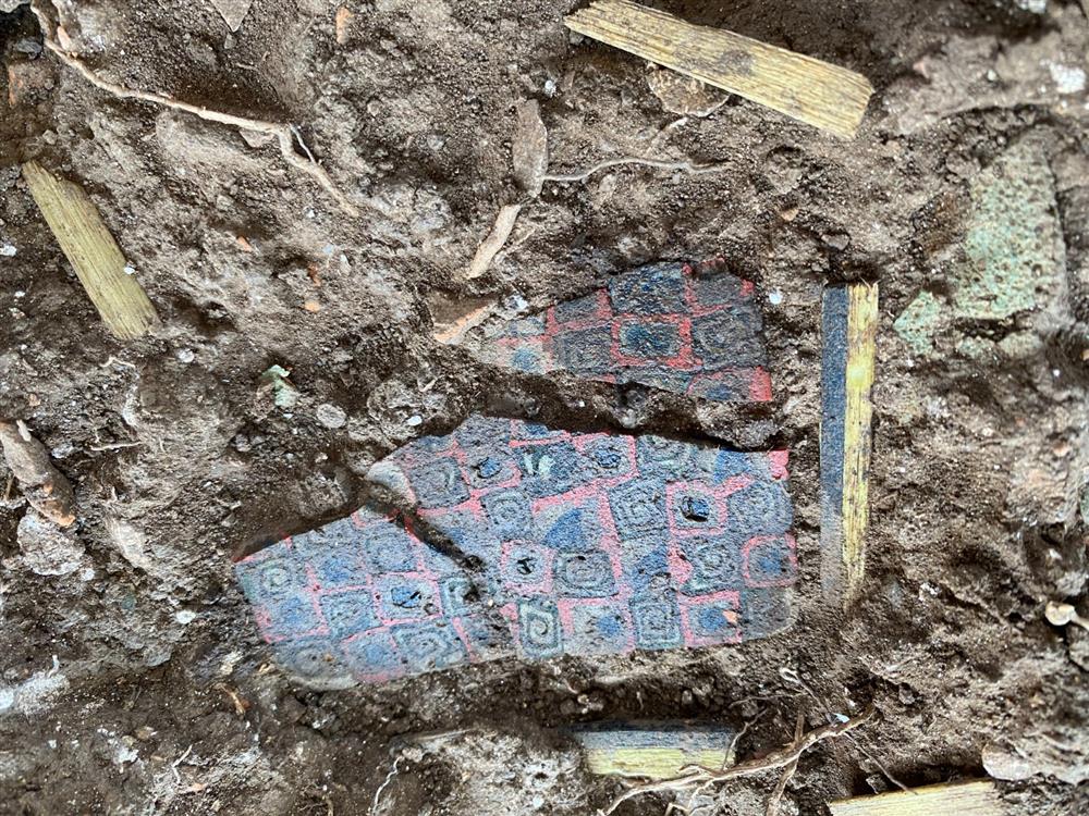 A photograph of a colorful Millefiori glass panel amongst the rubble of an archaeological dig site.