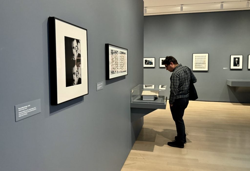 A man looks at photographs in a case in a museum gallery