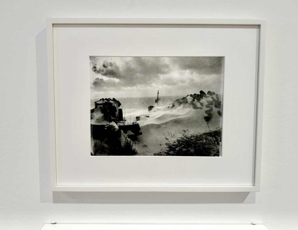 A black and white image of a snowy landscape displayed in a gallery