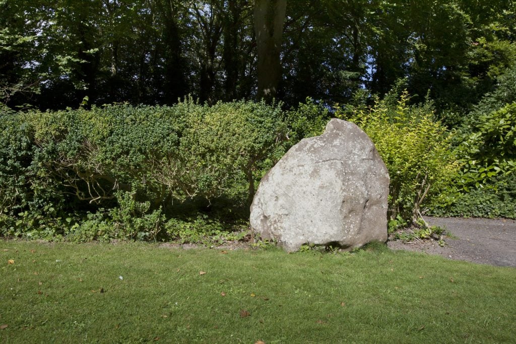 An ancient stone stands on a lawn