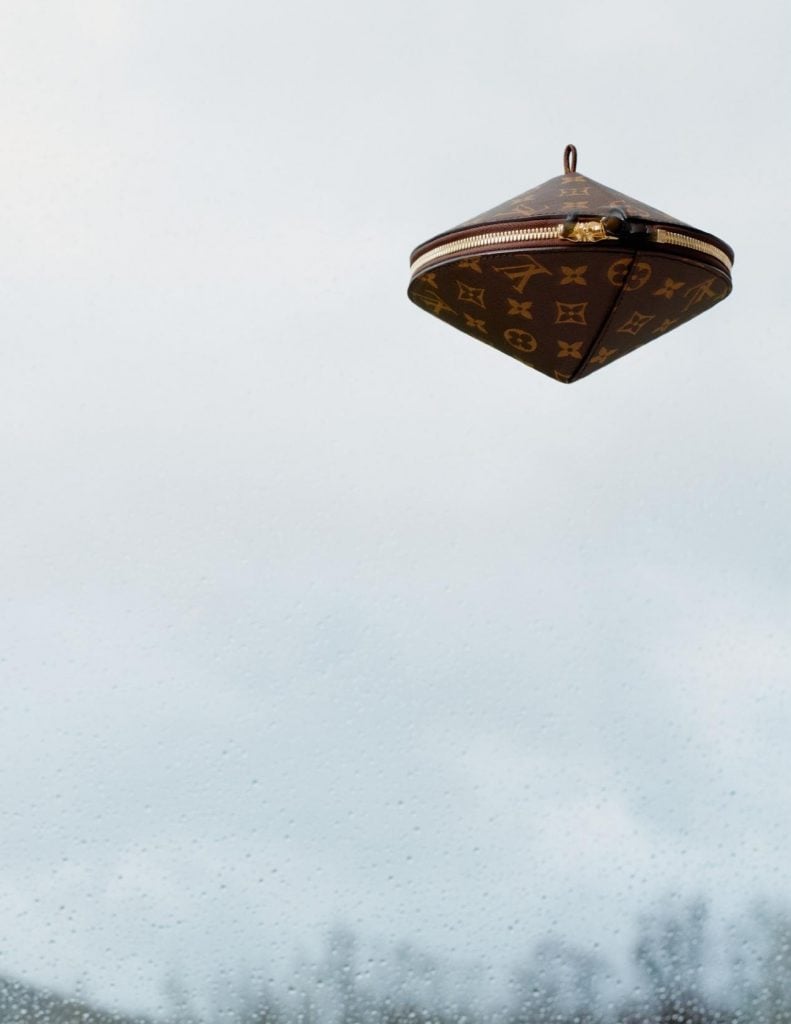 A photo of cloudy sky with a saucer shaped louis vuitton bag floating in the top right corner.