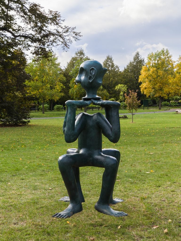 A 7-foot tall bronze sculpture of a figure with four legs facing down and four upturned legs in place of arms and a two-faced head installed in Regent's Park in London by Stephen Friedman Gallery for Frieze Sculpture.