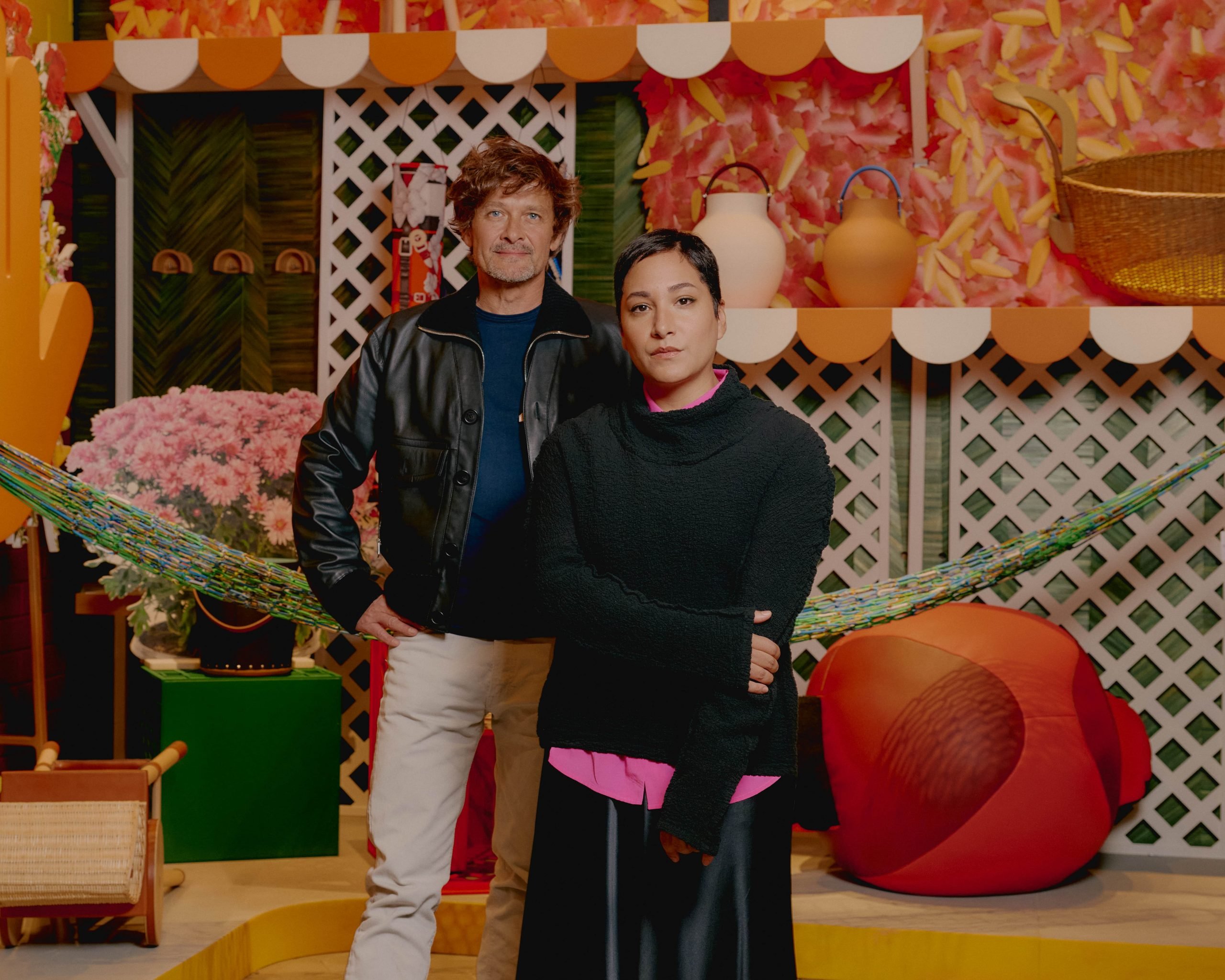 a man and a woman stand in a store that is outfitted like a wondrous colorful atelier