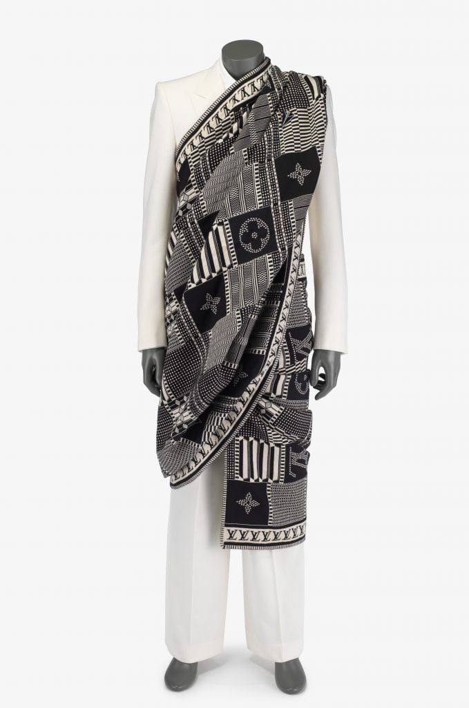 A black and white ensemble designed by Luis Vuitton is draped on a mannequin. A plain scarf with typical LV patterns is wrapped over a white suit.