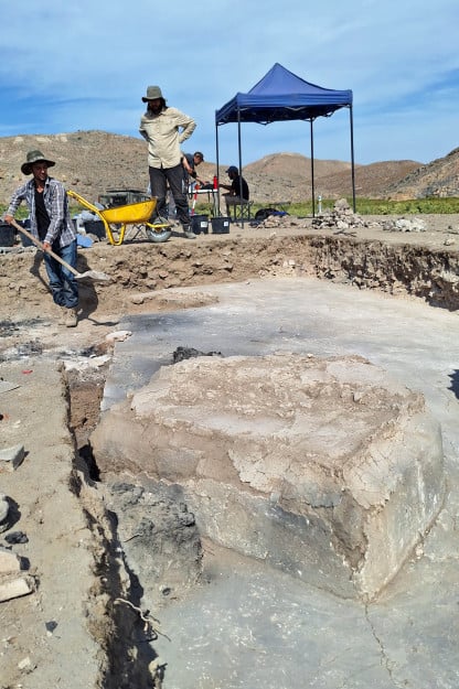 two men at work at an archeology site on a clear blue sky day