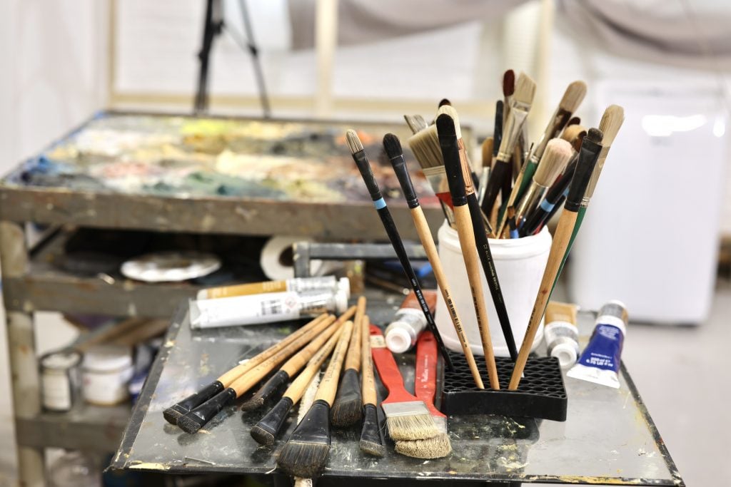 an artist studio with brushes inside and a rolling tray with paints on them