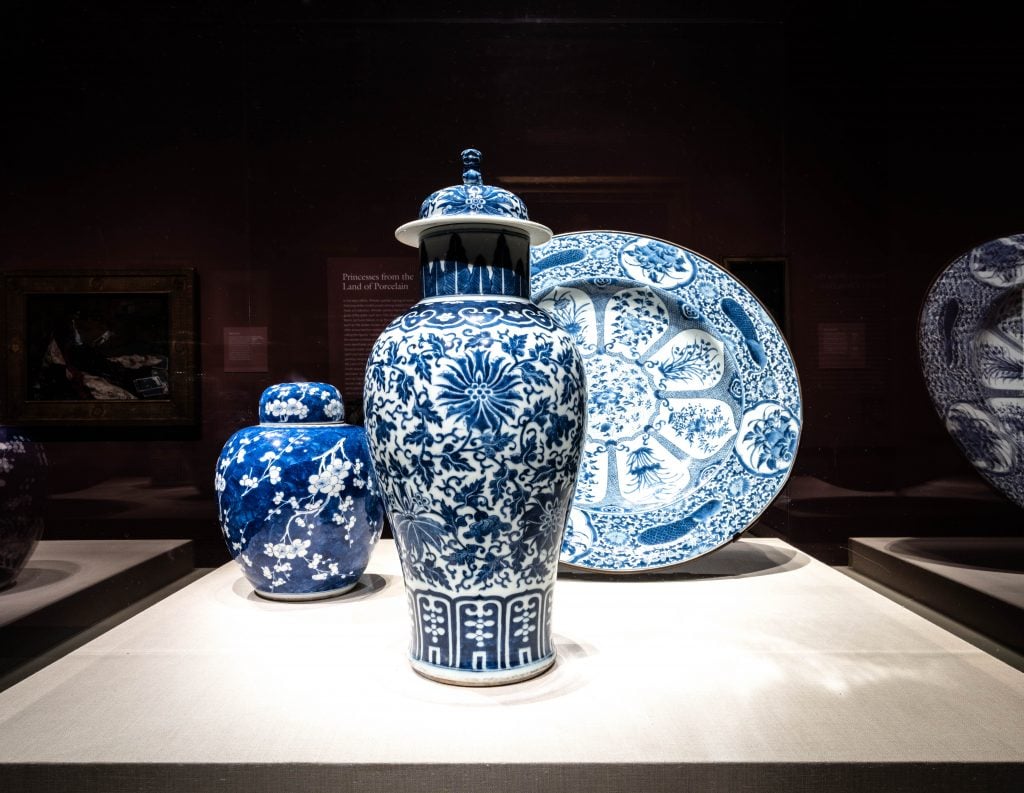 three blue and white porcelain pieces are encased in glass