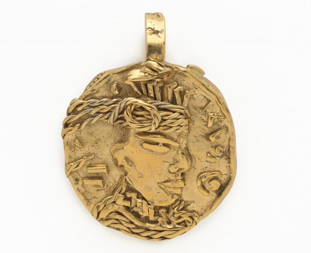 A gold pendant engraved with the figure of a jeweled man