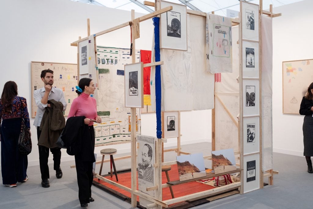 the interior of an art fair with people milling around large piece of art