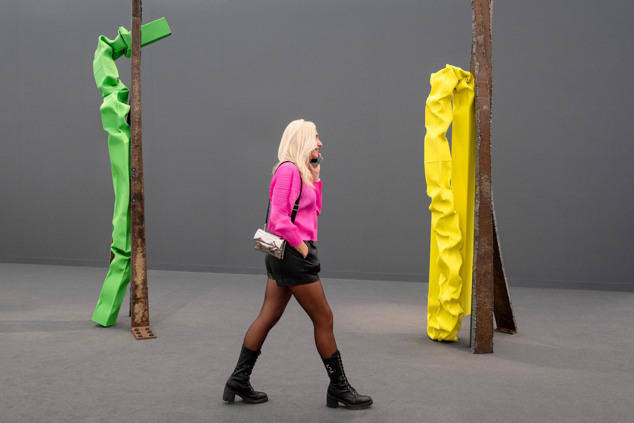 Woman in a pink sweater walking past colorful sculptures at Frieze art fair.