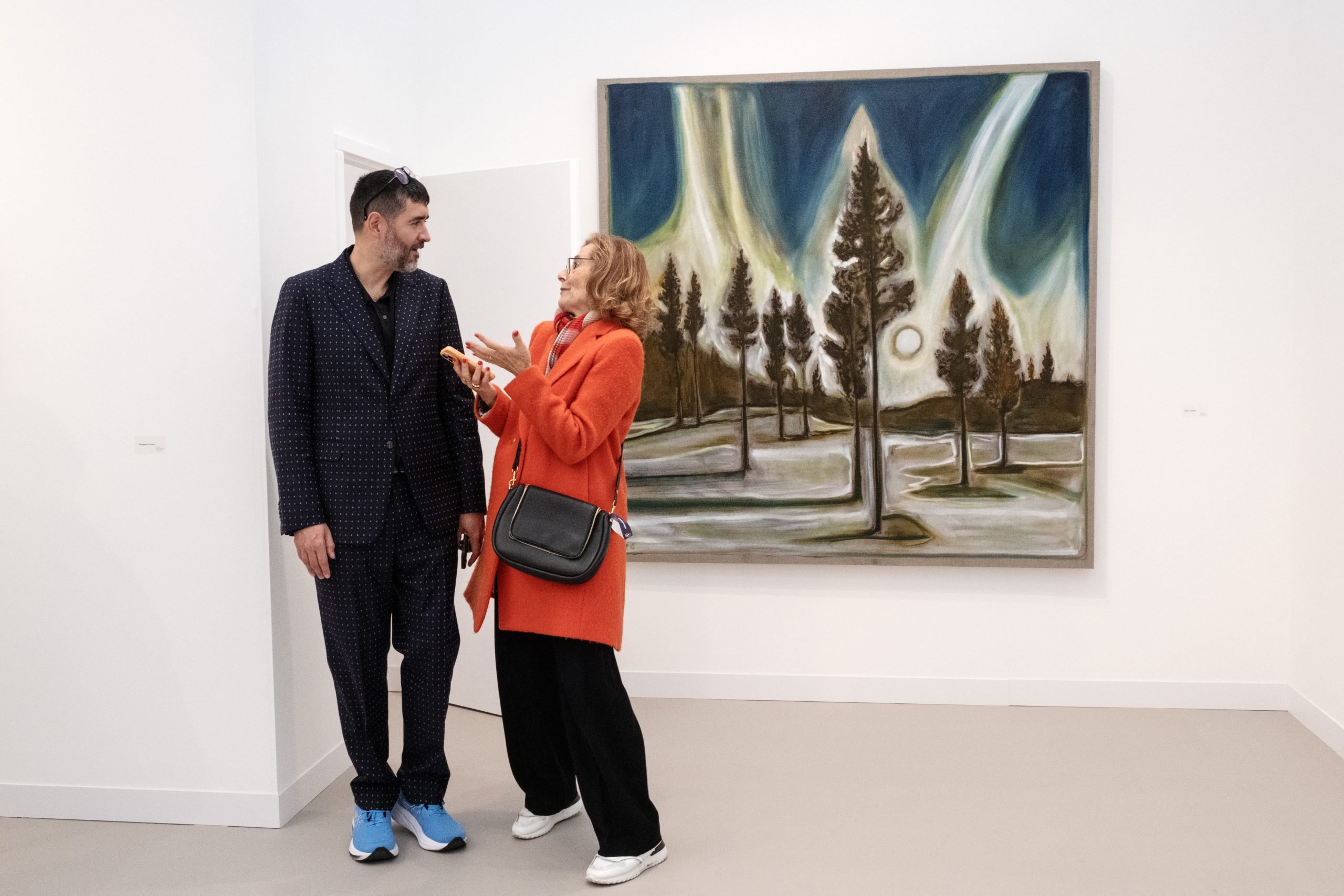 a man and a woman stand in front of a colorful painting