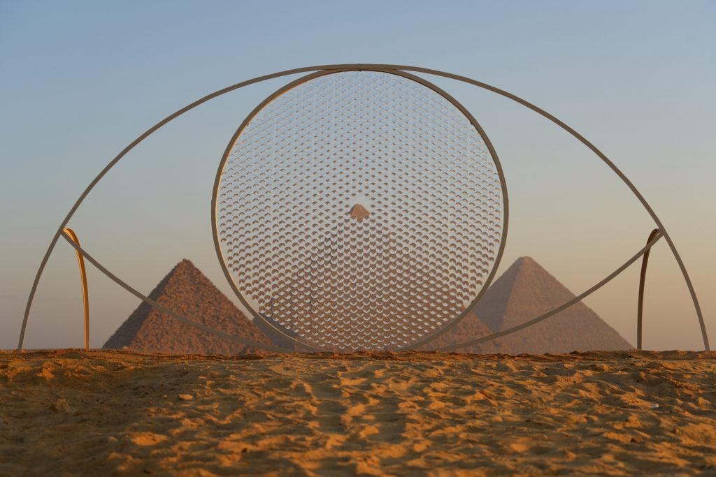 a circle and eye-shaped sculpture is set against hte pyramids