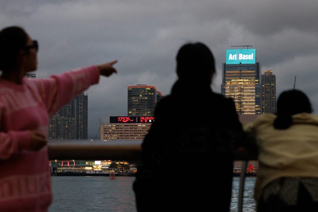 people looking out at the harbor with Art Basel Hong Kong sign across the water