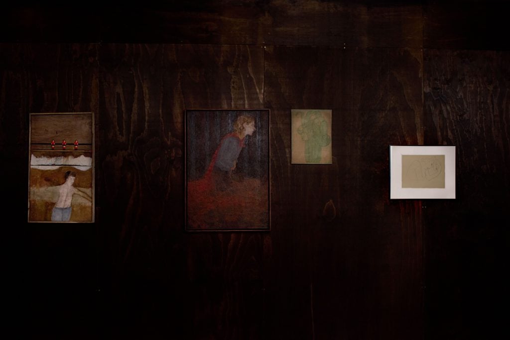 paintings line a darkened wall 