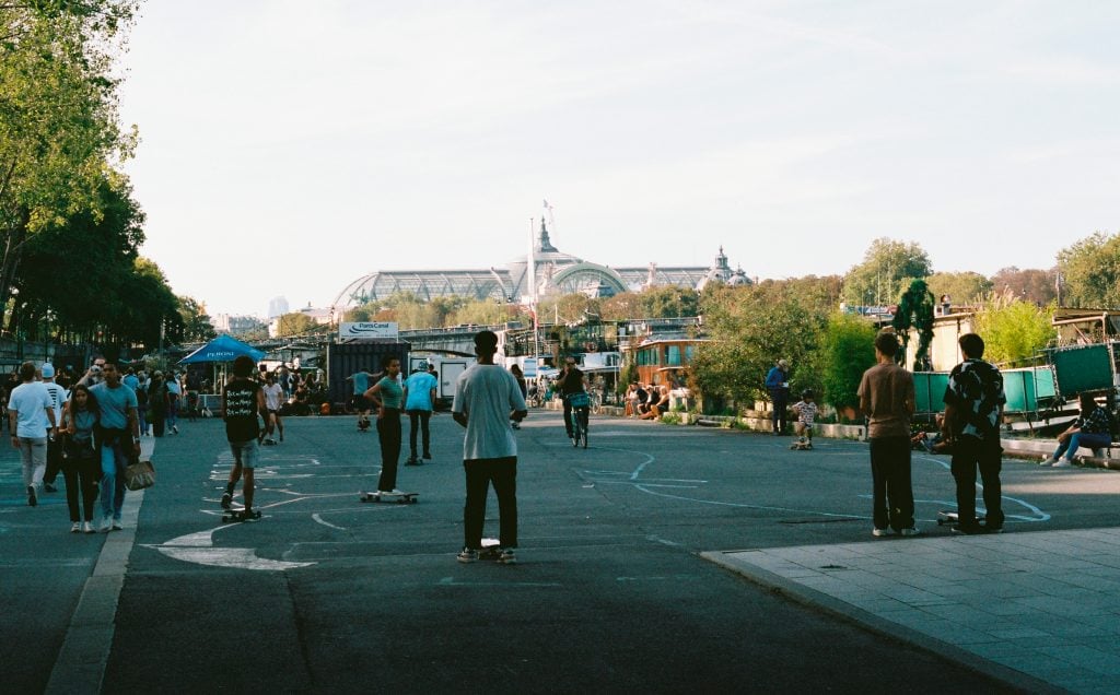 people walk, skateboard, hang out in the street outside Paris' Grand Palais