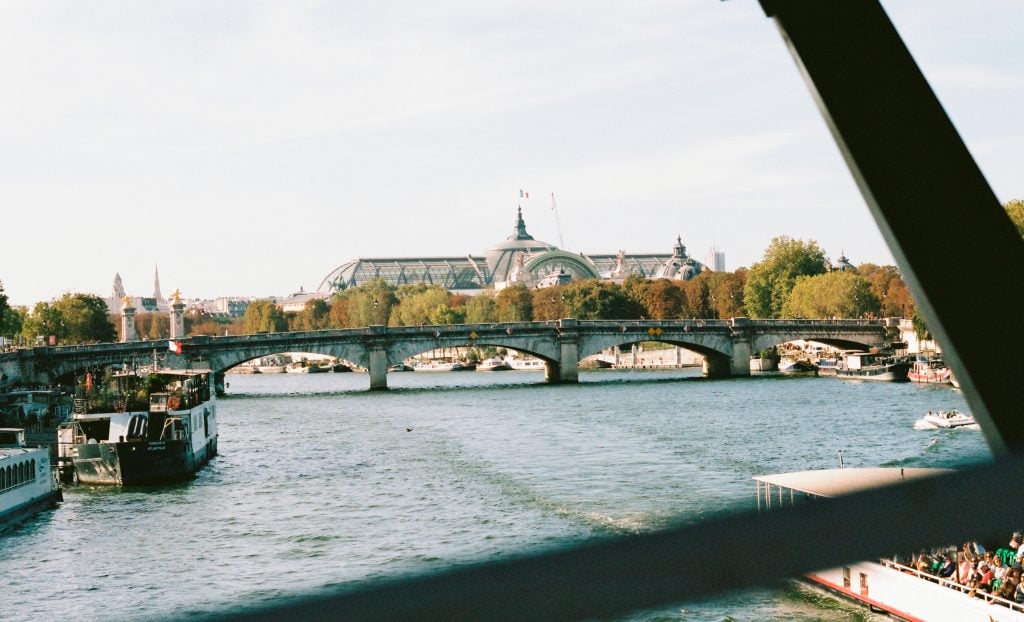 Scenic view of river and arched bridge with domed building in background.