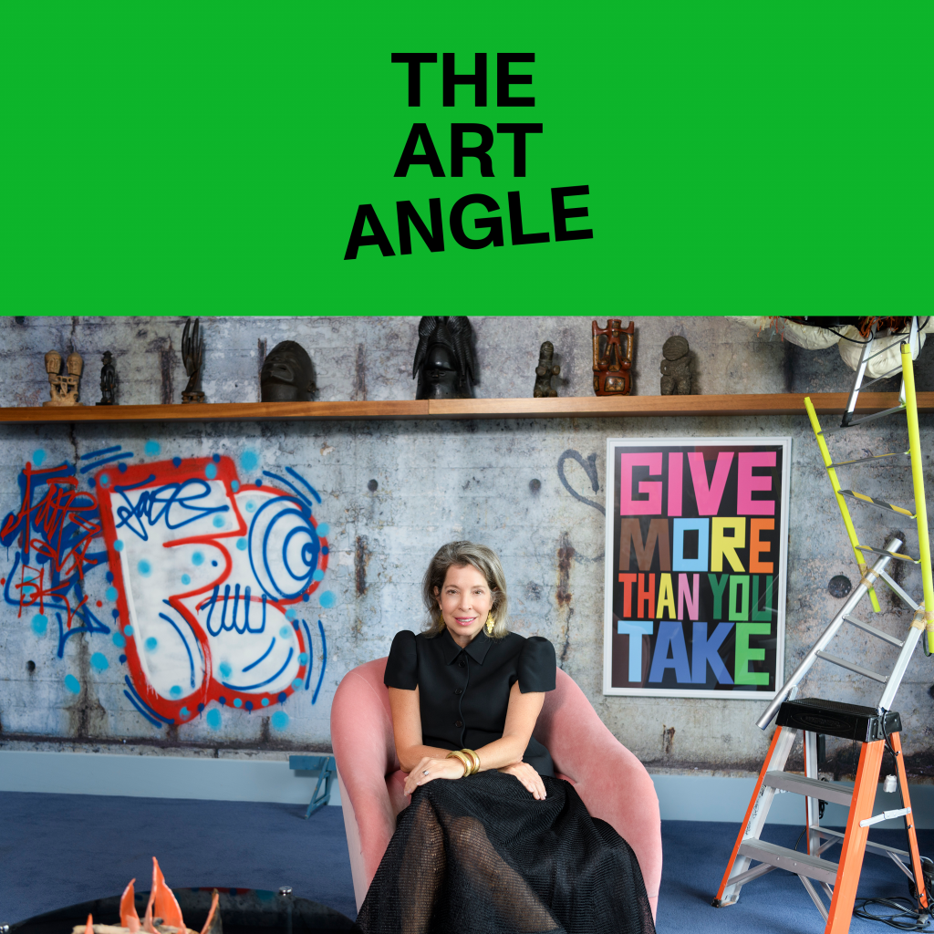 a white woman wearing all black sits in front of a concrete wall filled with colorful art and objects