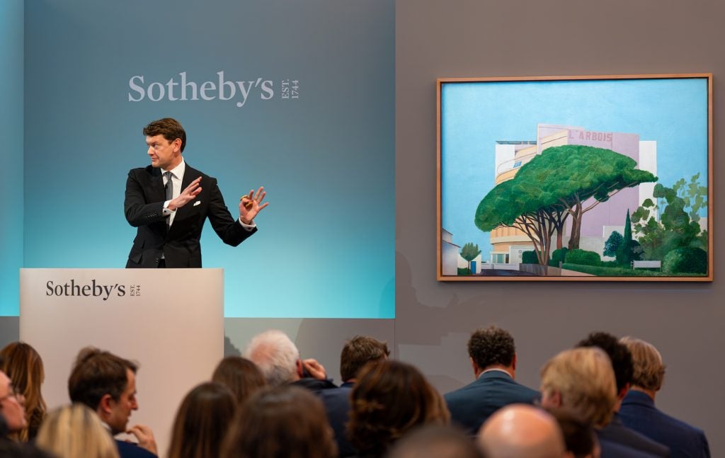 an image of auctioneer Michael Macauley selling David Hockney painting at London auction